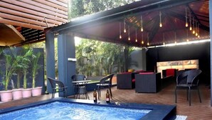 An outdoor pool area with seating and a covered patio. - Sky Taj Villa 5 BHK (Igatpuri)