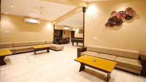 A spacious living area with a pool table, sofas, and a wall art piece. - Sky Taj Villa 5 BHK (Igatpuri)