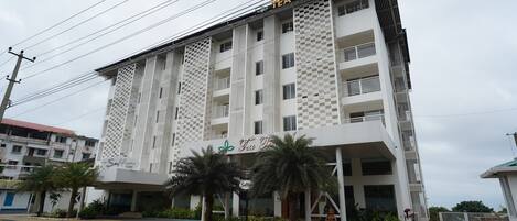 Un edificio de varios pisos con fachada a cuadros, un letrero que dice "Tea Tree Suites" y una palmera delantera.