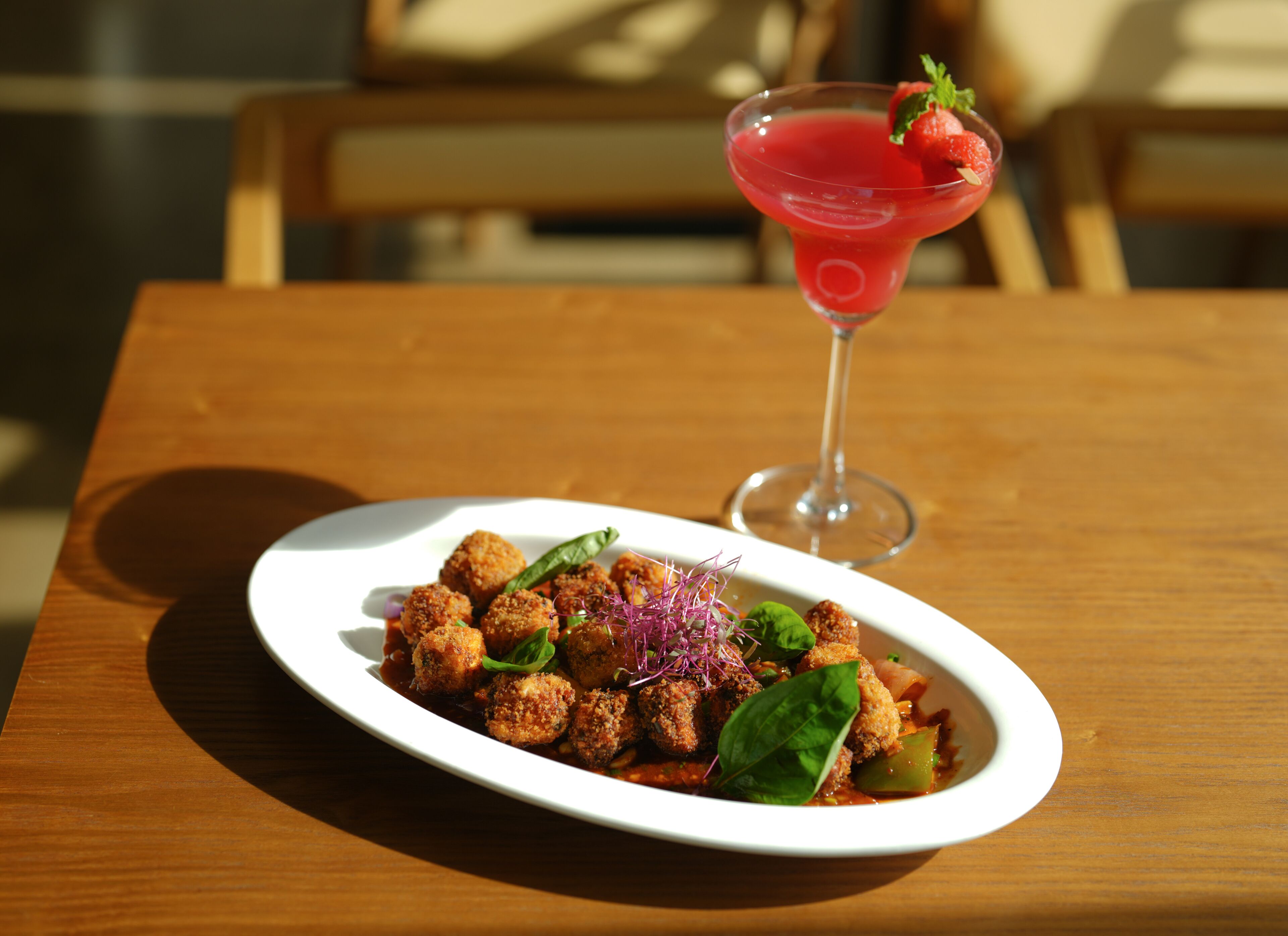 Een bord eten met een martini-glas ernaast.