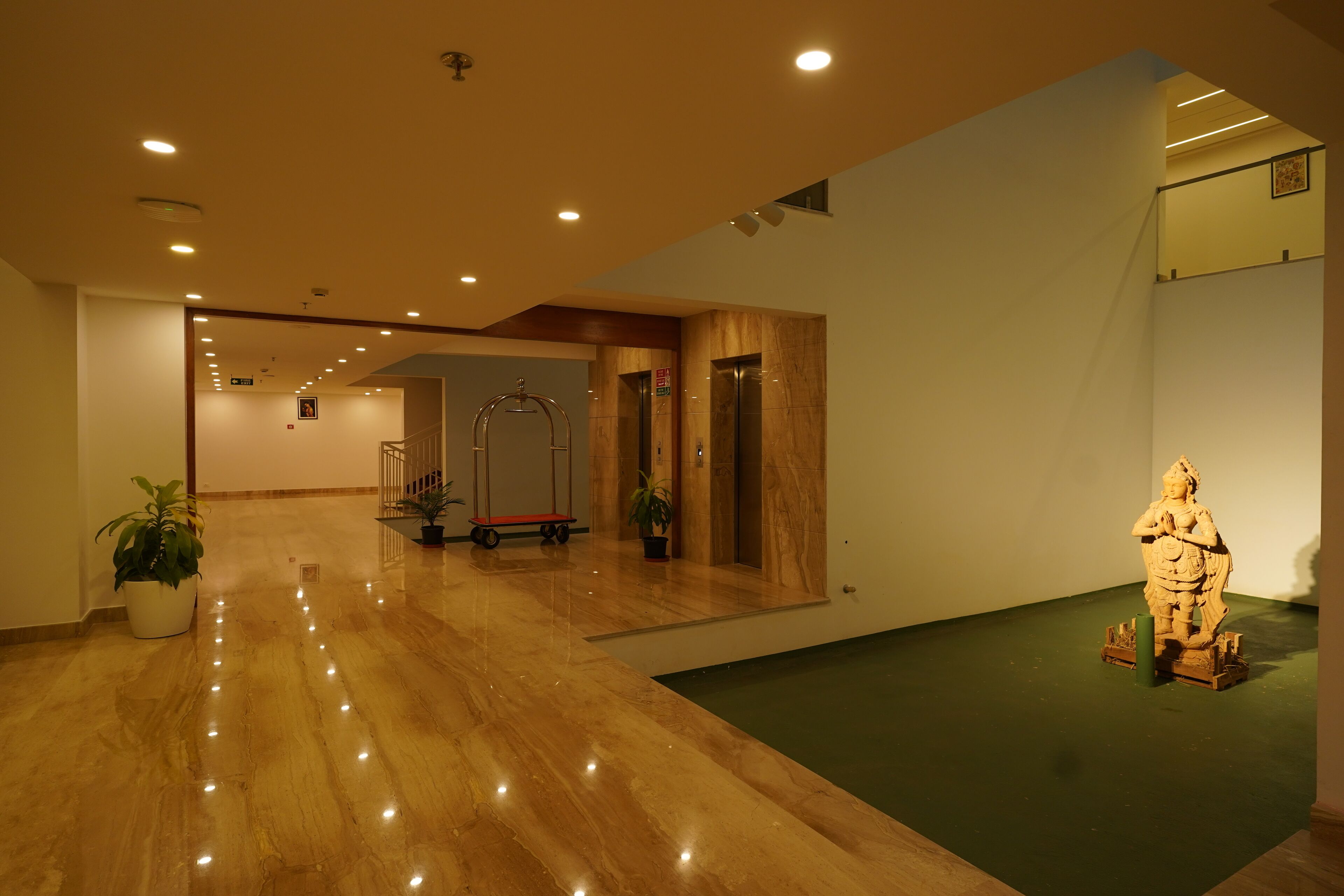 A spacious lobby with a polished marble floor, a large mirror, and a statue.