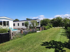 A residential area with a white house, a white mobile home, and a well-maintained lawn.