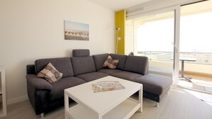 Un soggiorno moderno con un divano angolare grigio, un tavolino bianco e un quadro raffigurante un panorama cittadino.