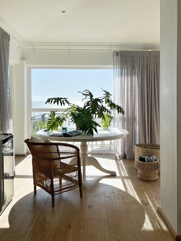 Un balcon avec une table ronde, une chaise en osier et des plantes en pot.