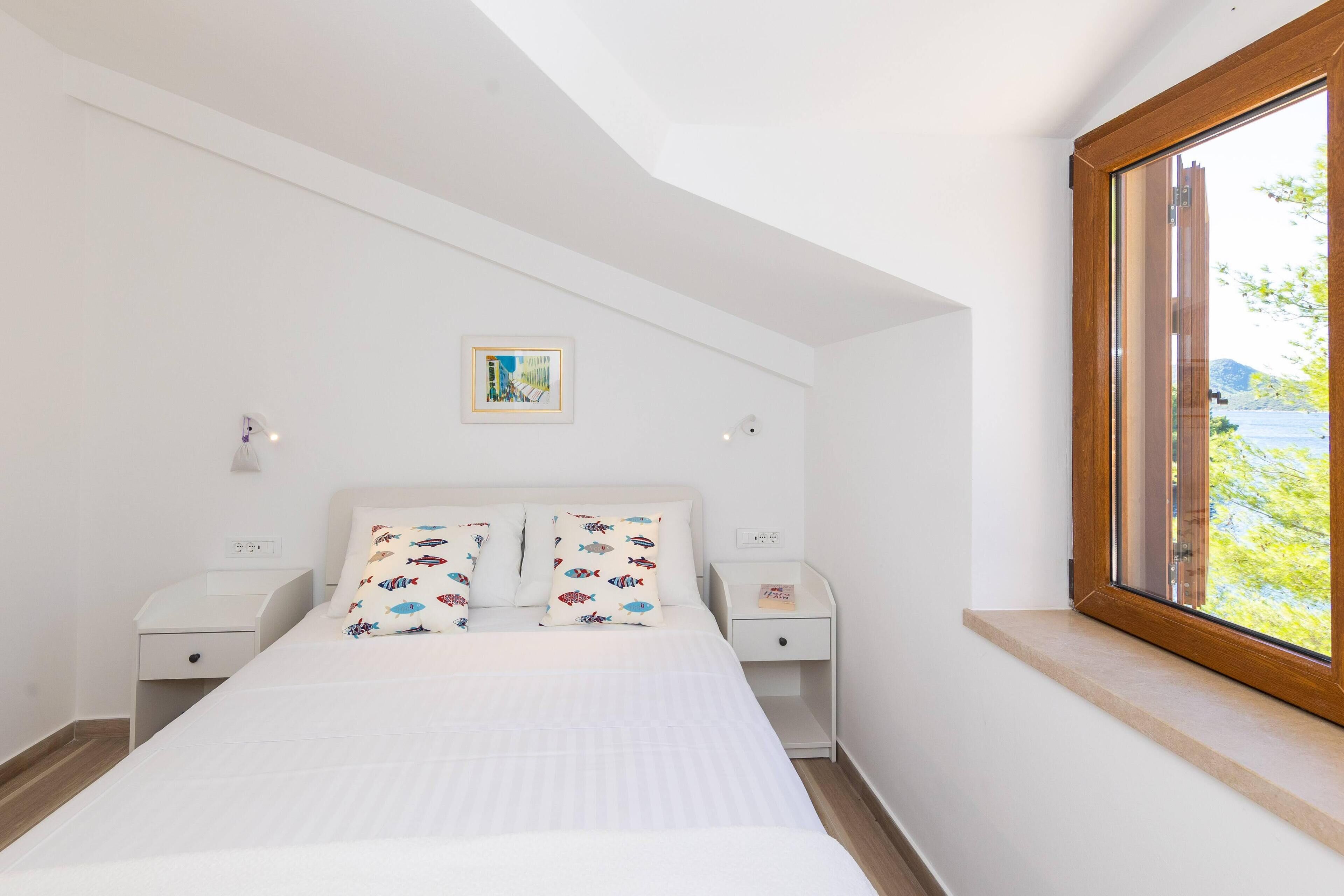 A bedroom with a bed, two nightstands, a window, and a picture on the wall.