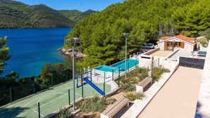 A coastal property with a tennis court, swimming pool, and a building with a red roof. - Beachfront Villa Brulupes (Ston)