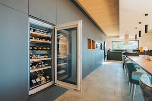 Enjoy a contemporary kitchen with wine refrigerator, sleek cabinetry, and large windows offering a view of the outdoors.