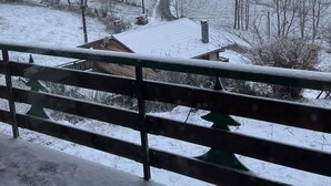 A snow-covered landscape with a winding road, a wooden fence, and a few buildings in the distance.