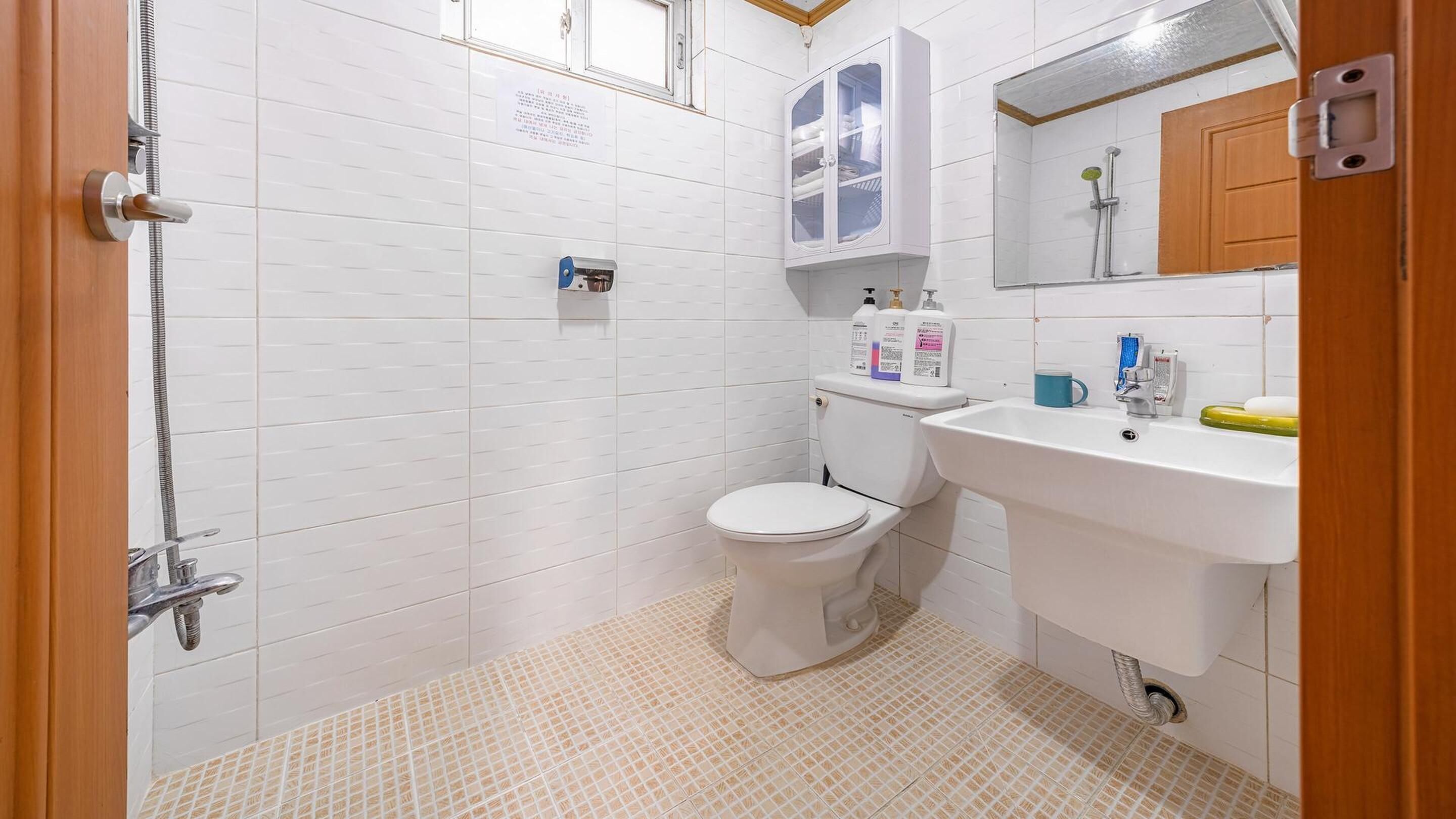 A bathroom with a shower, toilet, sink, and cabinet.