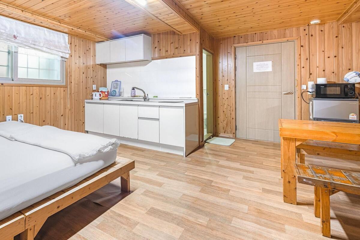 A compact room with a bed, a small kitchenette, and a dining area.