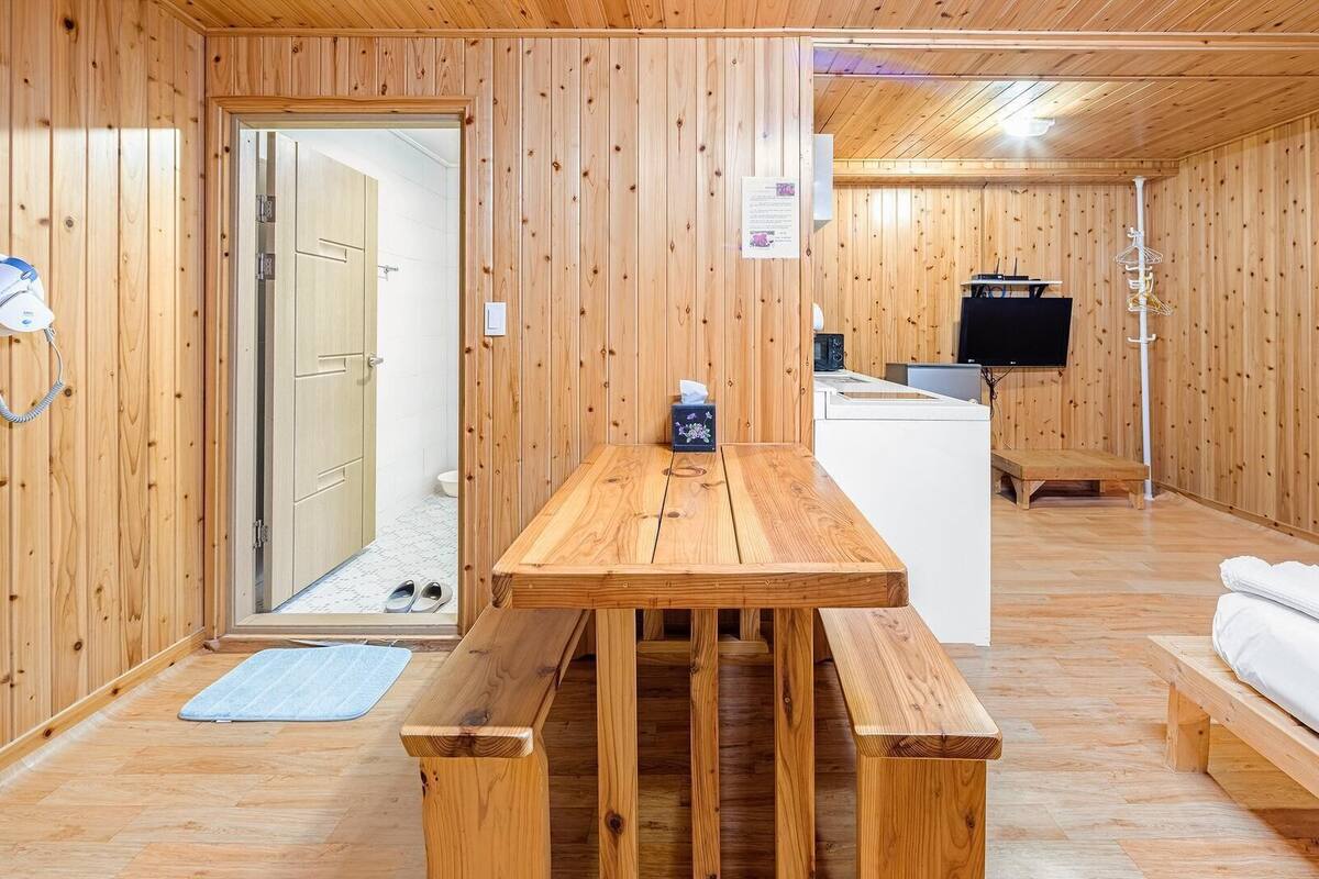 A wooden interior with a wooden table, bench, and white sofa.
