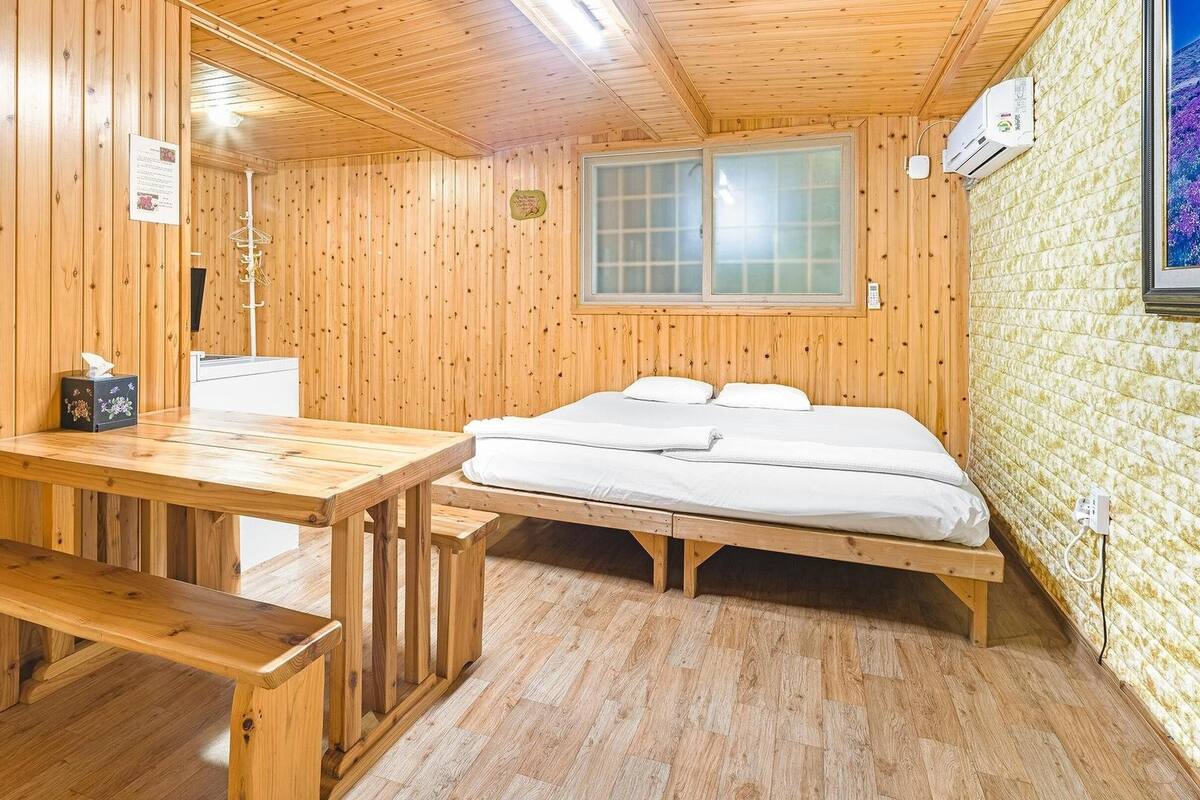 A wooden room with a bed, a table, and a bench.