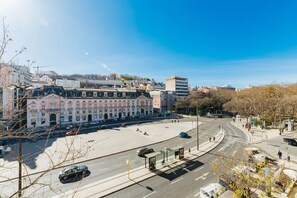 A cityscape with a prominent historic building, a wide street, and a clear sky.