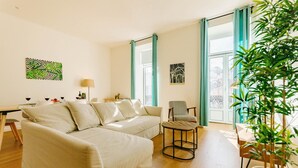 Una sala de estar moderna con sofá, sillones, una mesa de centro y una zona de comedor.