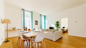 Un espacio habitable moderno y de planta abierta con zona de comedor, sofá y televisor.