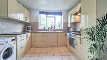 Enjoy cooking in this well-equipped kitchen with a washing machine, stainless steel stove, and ample storage space.