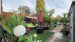 Un espace patio aménagé avec une balançoire, des sièges d’extérieur et des plantes en pot.