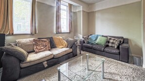 Un salon avec deux canapés, une table basse en verre et une fenêtre avec des rideaux.