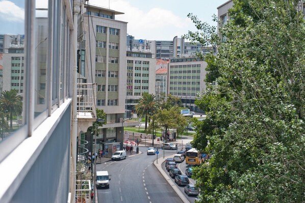 A street view with modern buildings, parked cars, and a bus.