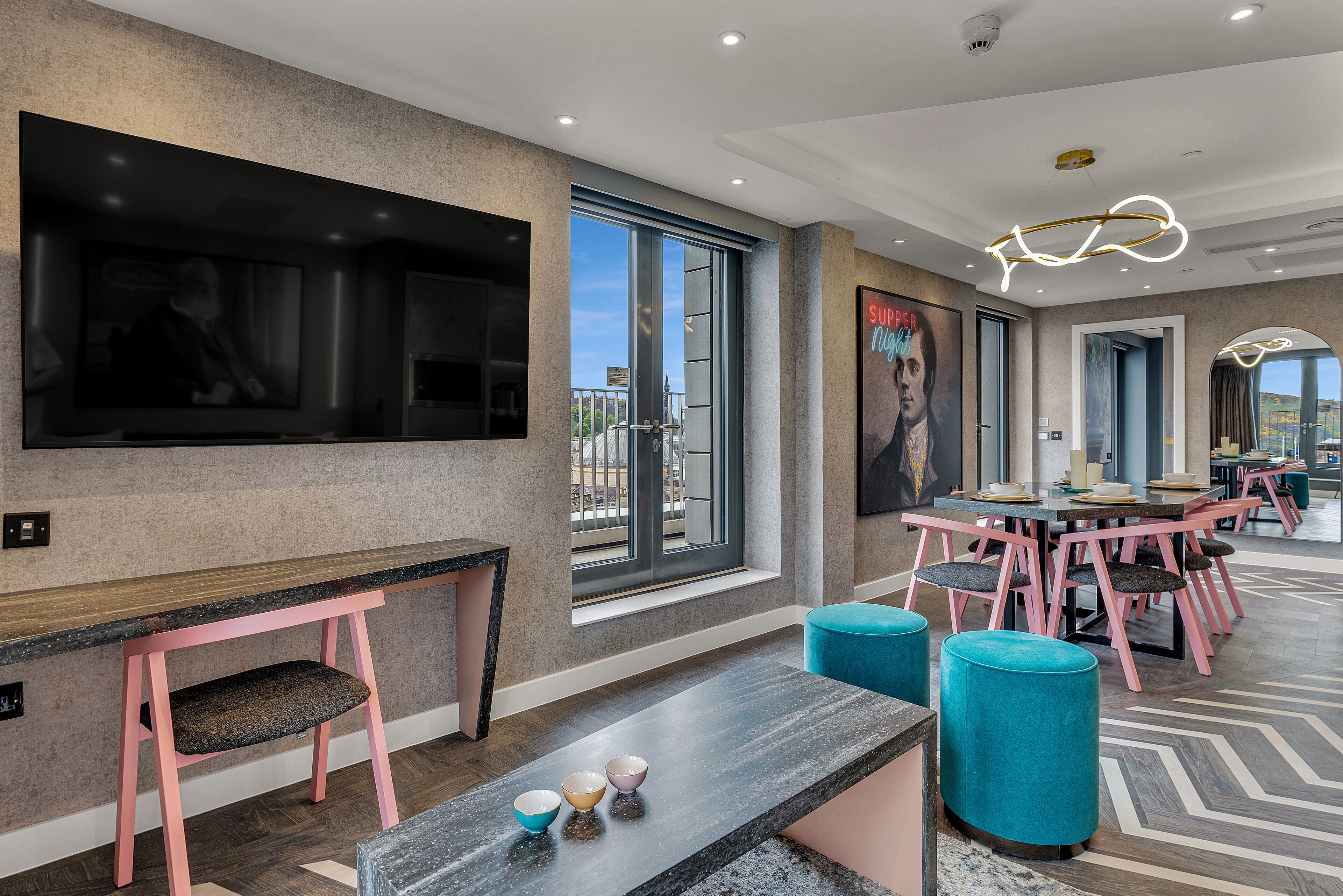 A modern hotel lobby with a large TV, seating area, and a view of the outdoors.