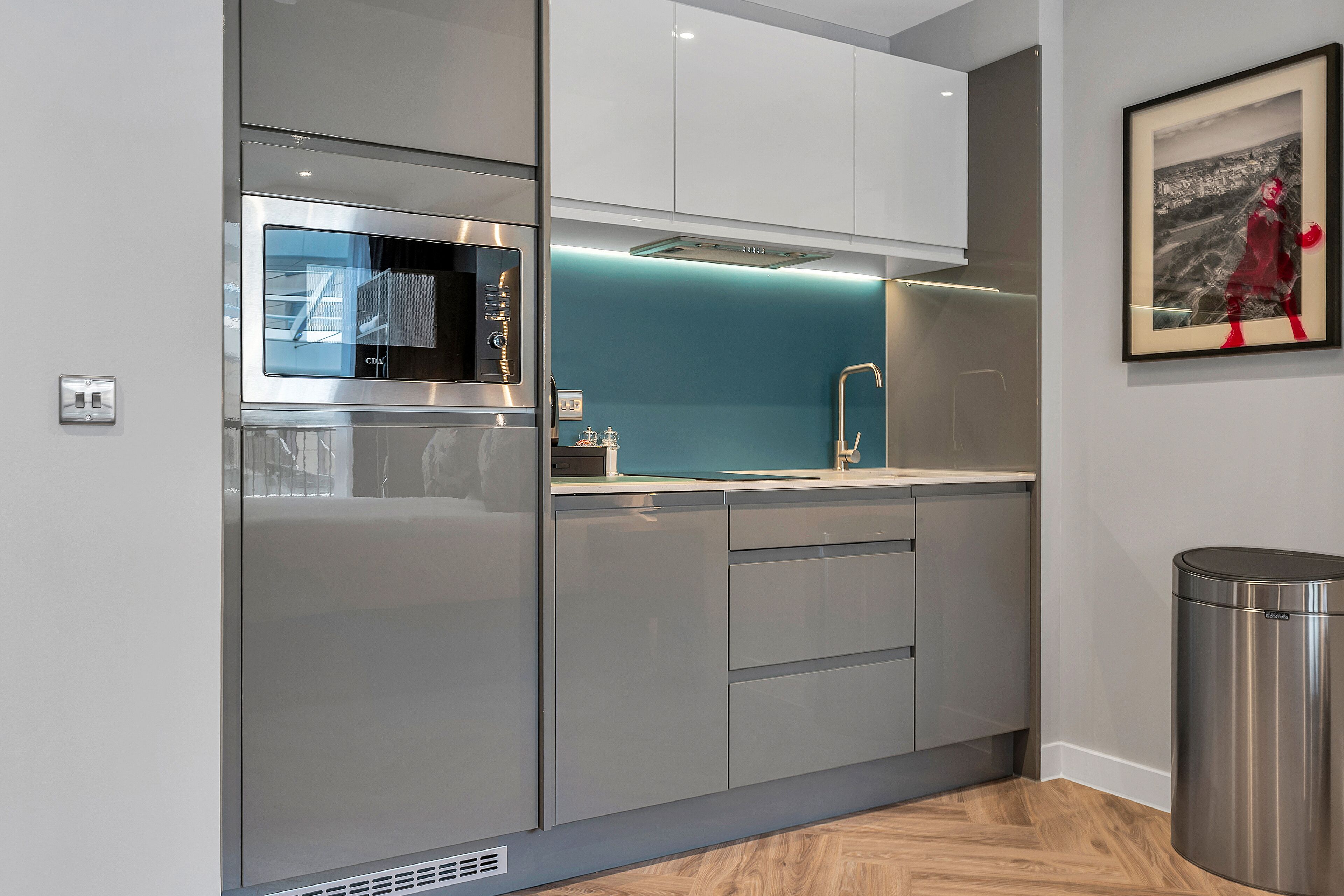 A modern kitchen with stainless steel appliances, a blue backsplash, and white cabinetry.