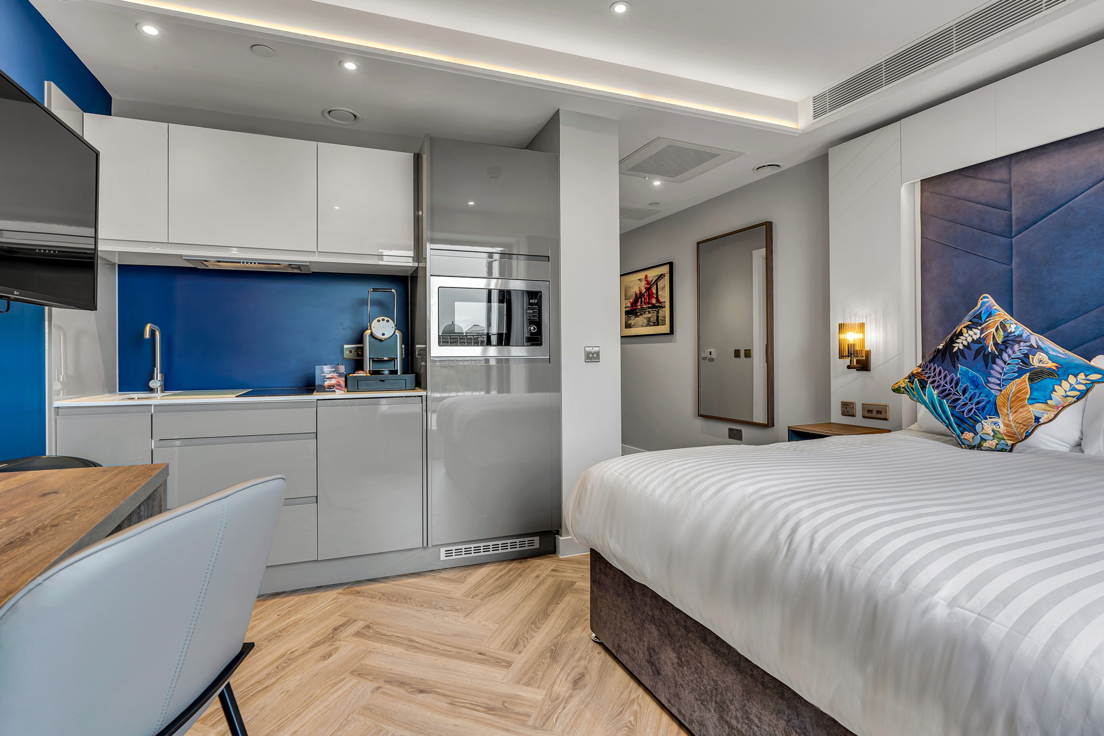 Una habitación de hotel moderna con kitchenette, una cama grande y baño.