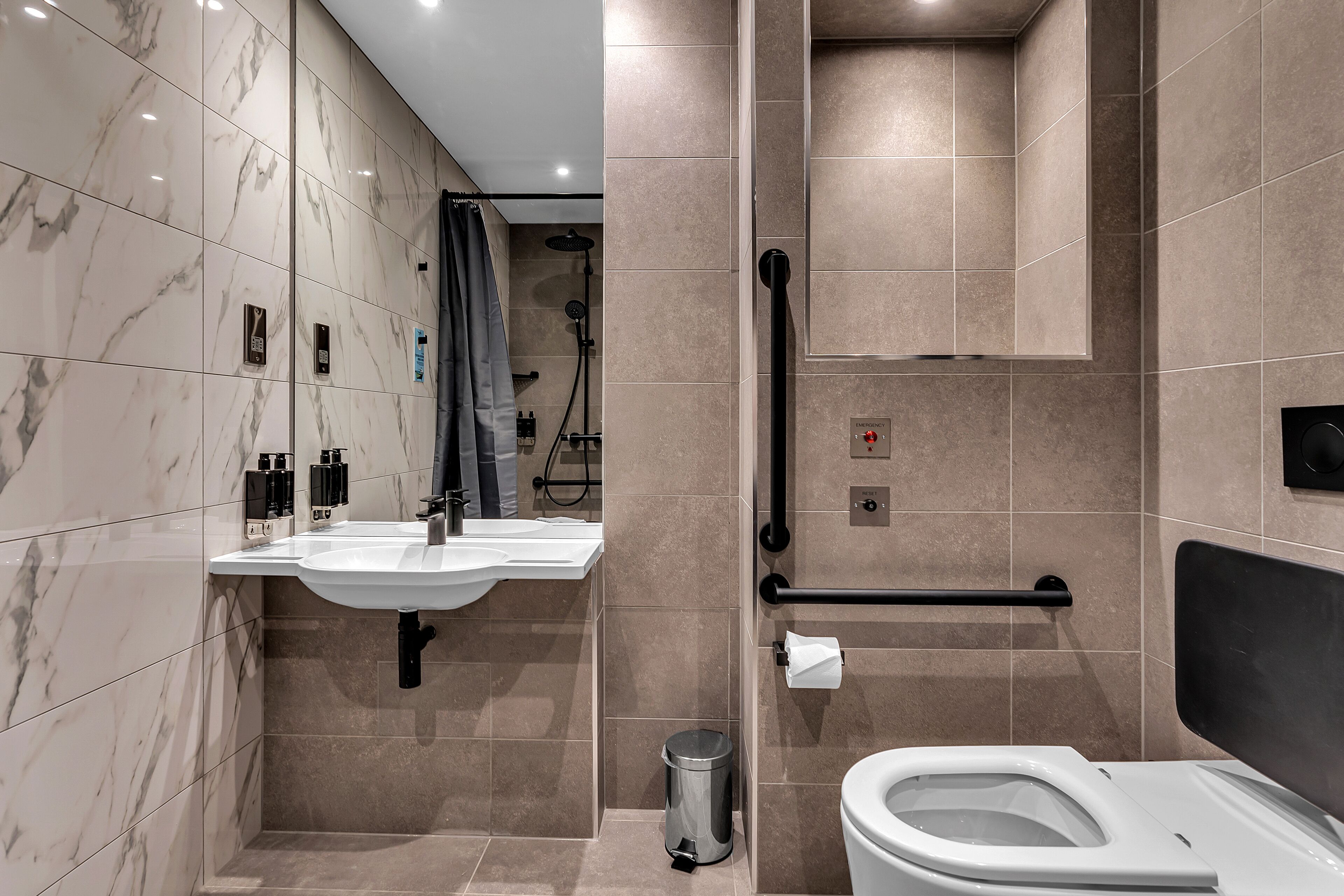 A modern bathroom with a marble vanity, a toilet, and a shower area.