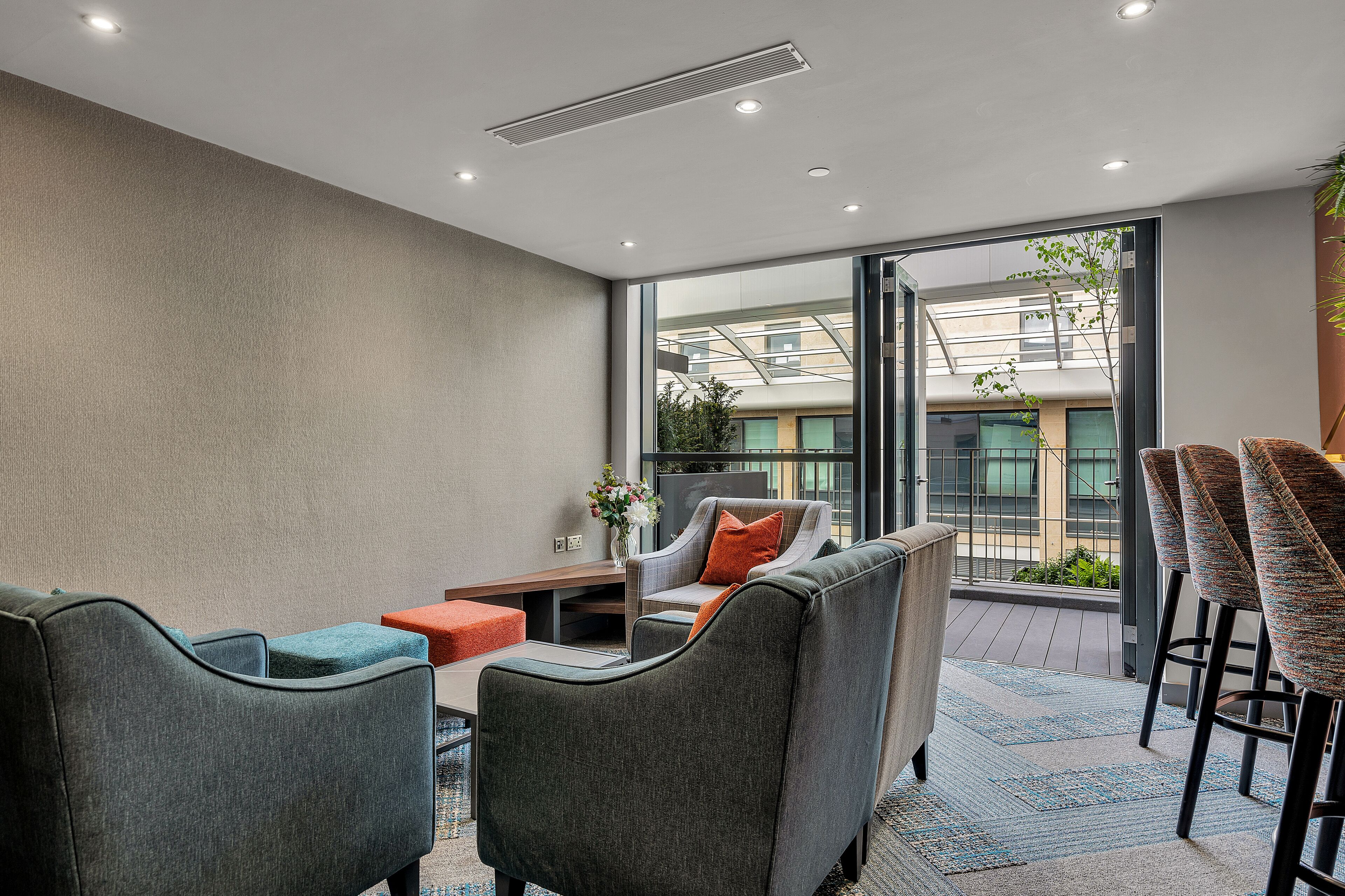 A modern lounge area with a sofa, chairs, and a bar area with stools.