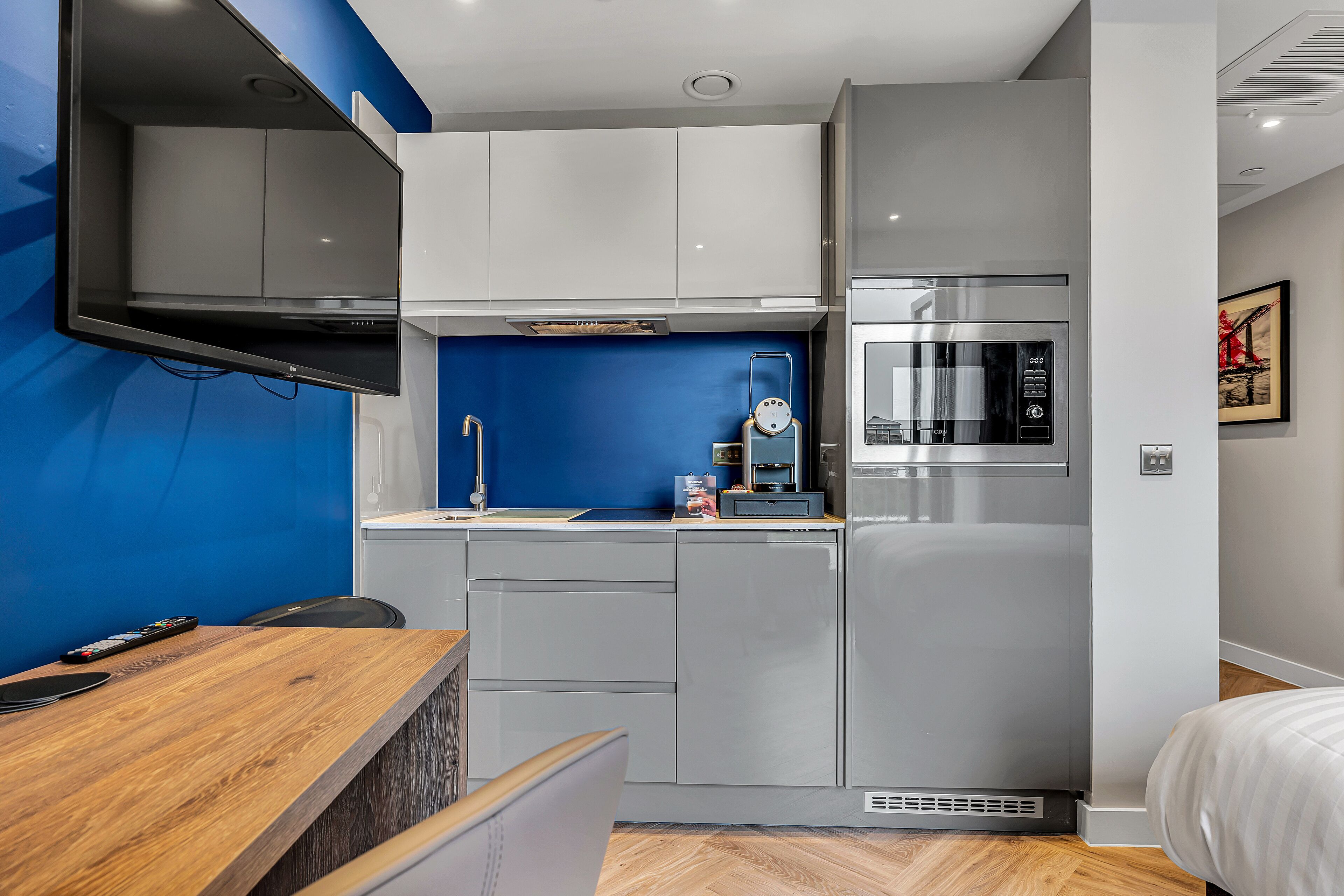 A compact kitchen with grey cabinets, a microwave, and a built-in oven.