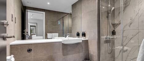 A modern bathroom with a glass-enclosed shower, a vanity with a sink, and a toilet.