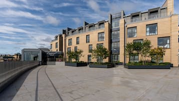 A modern building with a flat roof, large windows, and a paved walkway.