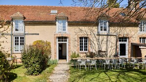 A traditional building with a tiled roof, a central entrance, and a patio area with outdoor seating. - Gîte 14 people - 5 bedrooms - 5 bathrooms - Large spaces (Fontaine-sur-Ay)