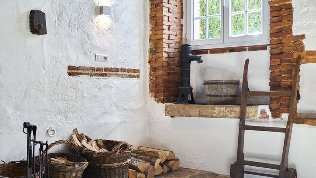 A rustic room with a wooden bench, a window with a view of greenery, and a fireplace with a chimney. - Gîte 14 people - 5 bedrooms - 5 bathrooms - Large spaces (Fontaine-sur-Ay)