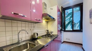 A kitchen with a stainless steel sink, a gas stove, and pink cabinets.