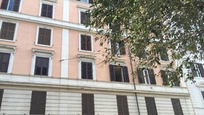 A multi-story building with a row of windows and shutters.