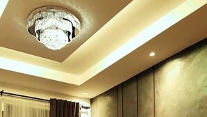 Ein modernes Wohnzimmer mit einem dunkelbraunen Sofa, einem Holztisch, einer Topfpflanze und einer großen Wandverkleidung.