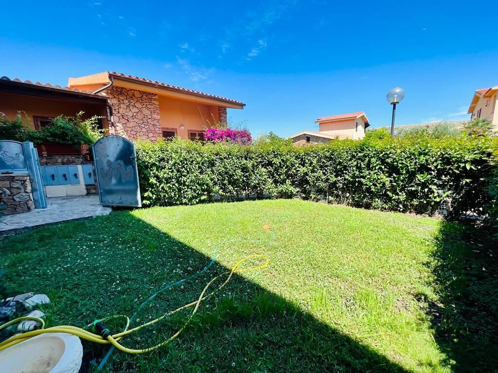 A well-maintained backyard with a lawn, a stone wall, and a metal gate.