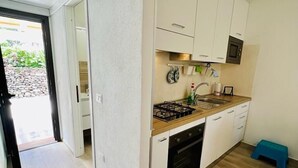 A modern kitchen with white cabinets, a gas stove, and a microwave. - Residence Oasi La Cinta Centro (San Teodoro)