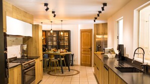 Una cocina moderna con armarios de madera, estufa de acero inoxidable y comedor con mesa y sillas redondas.