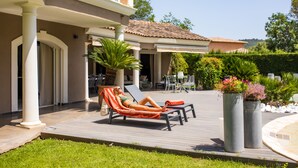 Un espacio al aire libre iluminado por el sol, con piscina, sillones de descanso y una terraza con mesa y sillas.