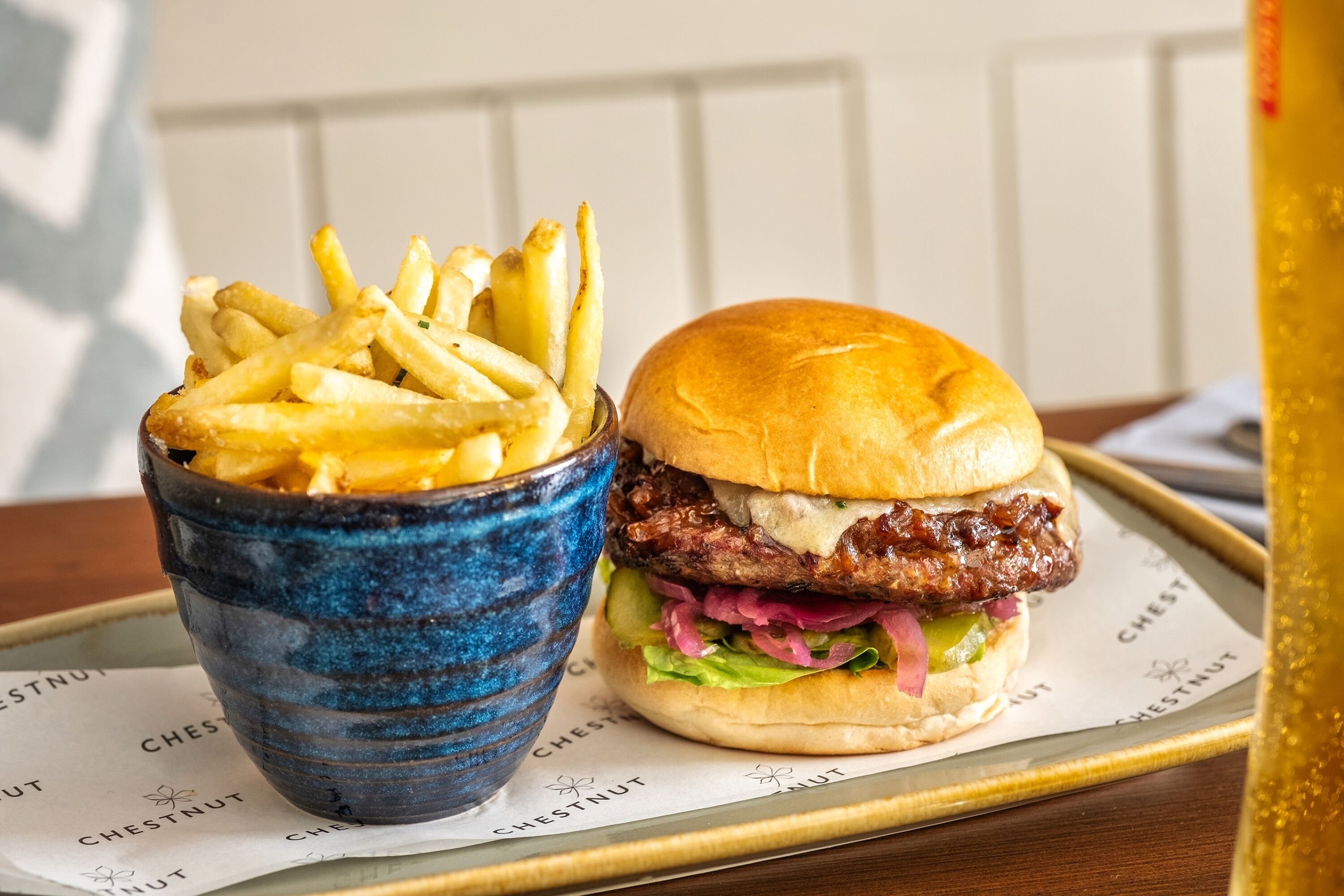 A burger with fries on a tray.