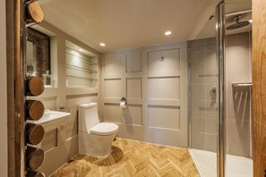 Features a large mirror, white toilet, and glass-enclosed shower.