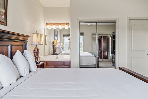 A hotel room with a large bed, a vanity with a mirror, and a walk-in closet.