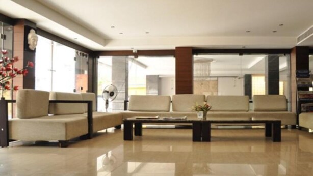 A modern lobby with a sofa set, a coffee table, and a decorative vase. - Hotel Shaans (Tiruchirappalli)