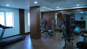 A gym with treadmills, elliptical machines, and free weights. - Hotel Shaans (Tiruchirappalli)