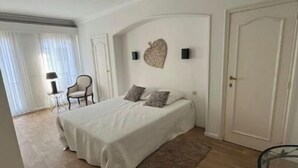 Un dormitorio con cama, silla, mesa y puerta.