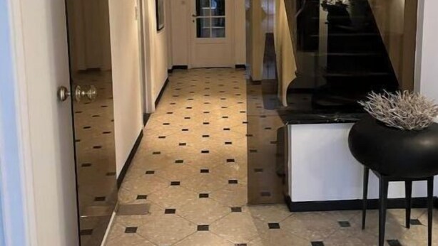 Un pasillo con piso de diseño geométrico, un candelabro y una escalera.
