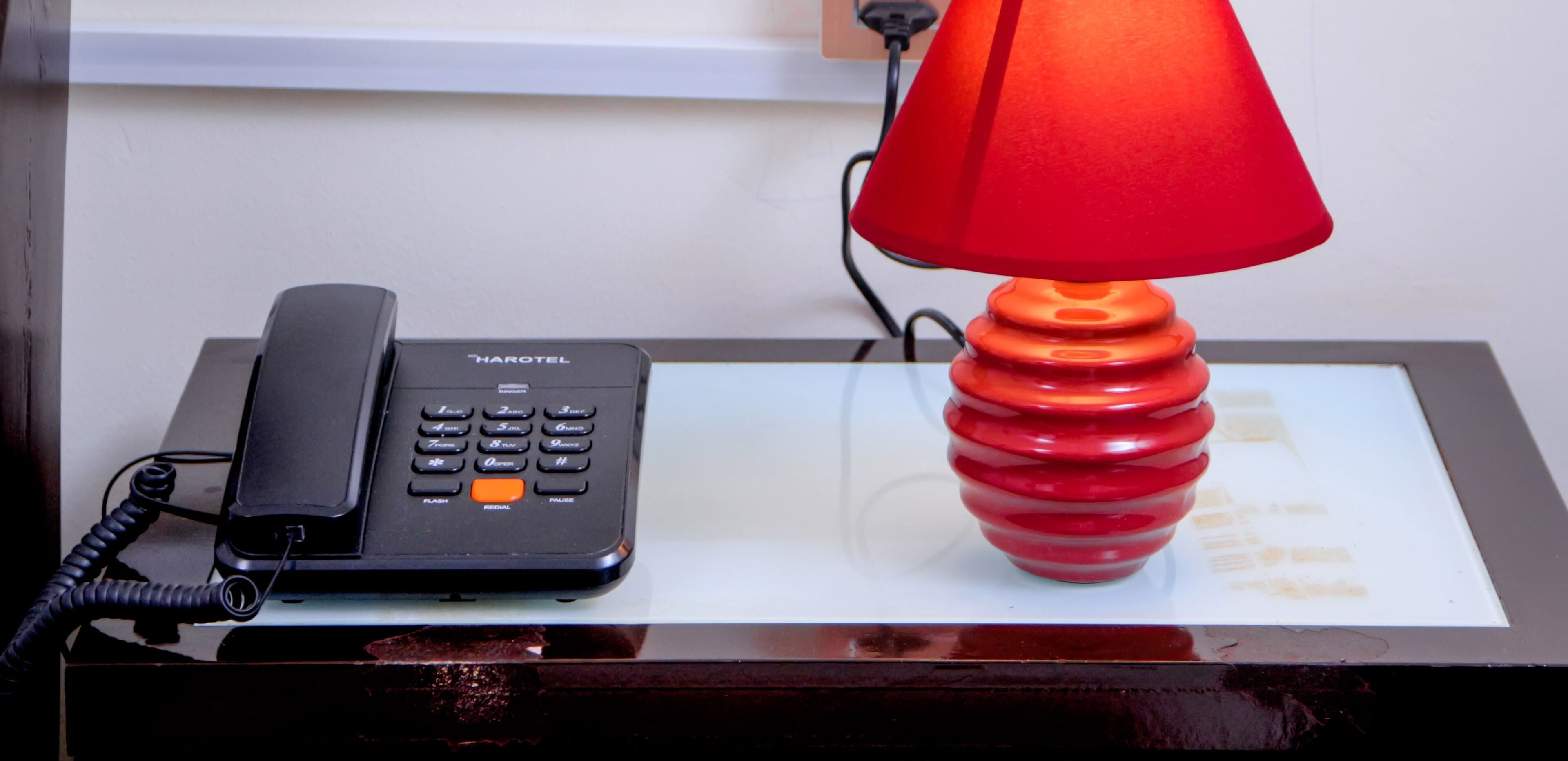 A Harotel phone and a red lamp on a desk.
