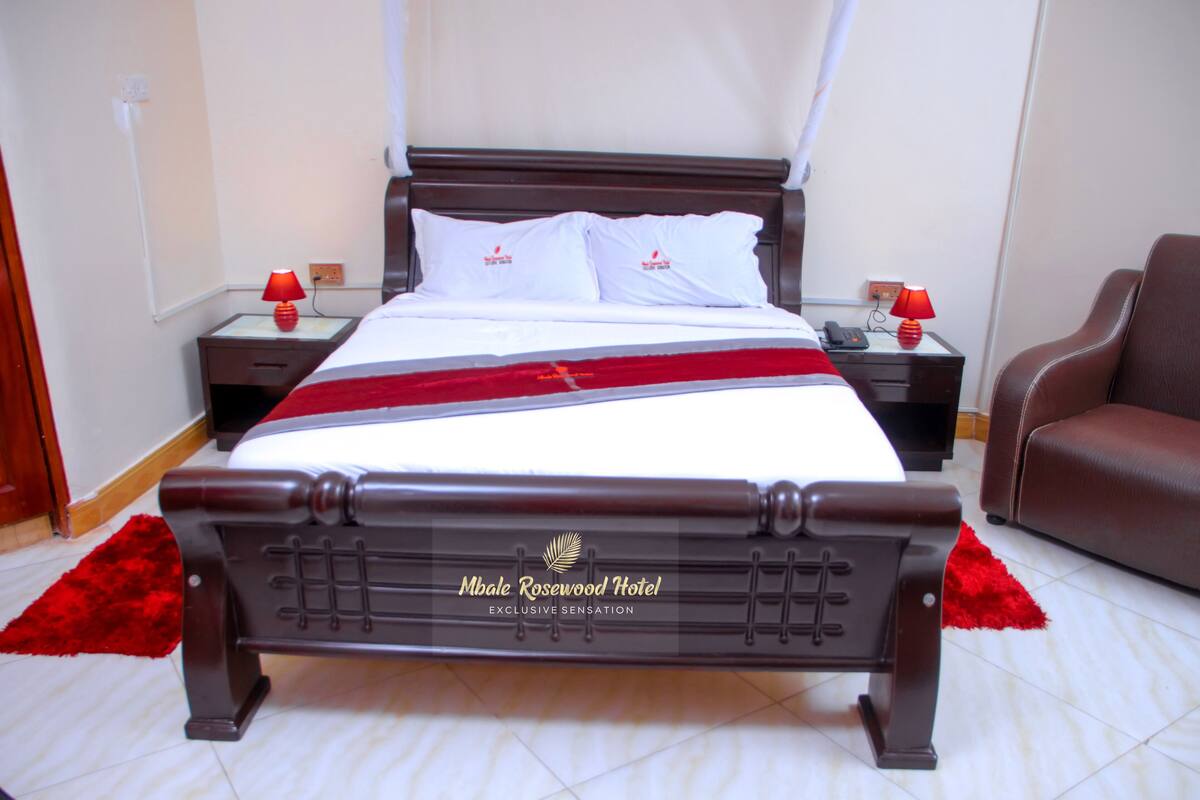 A bed with a headboard labeled "Mbale Rosewood Hotel Exclusive Sensation."