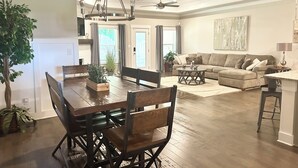A spacious living area with a dining table, sofas, and a chandelier.